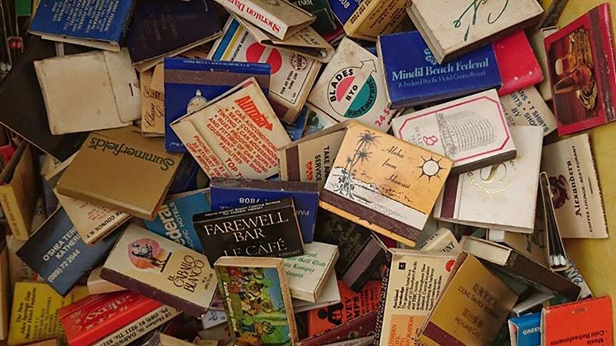 A collection of vintage matchboxes scattered in a box.