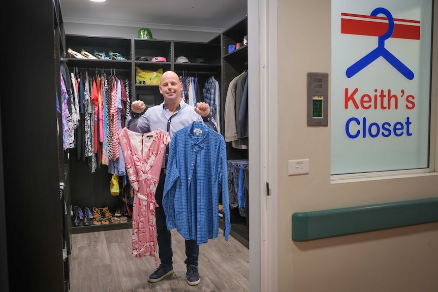 Keith Donnelly holding up two articles of clothing inside the closet he's made.