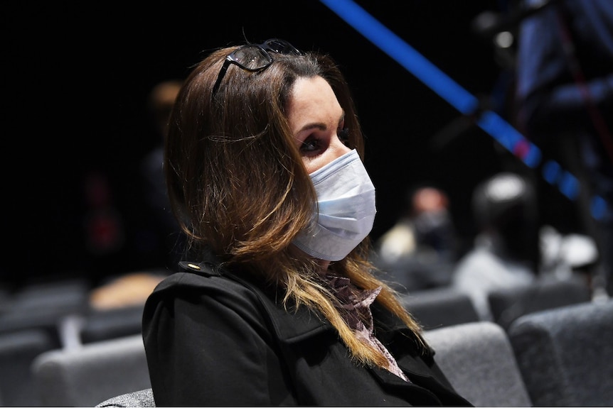 Peta Credlin, wearing a surgical mask, sits at a press conference.