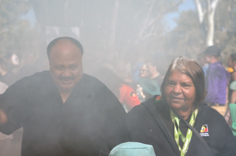 The pair walk together through a haze of smoke
