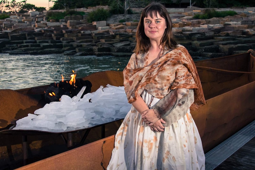 Woman standing next to large sculpture canoe.