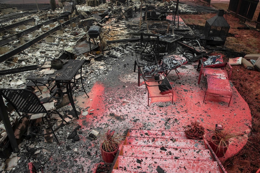 The charred wreckage of a burned out home and its contents is seen scattered across the home's foundation concrete slab.