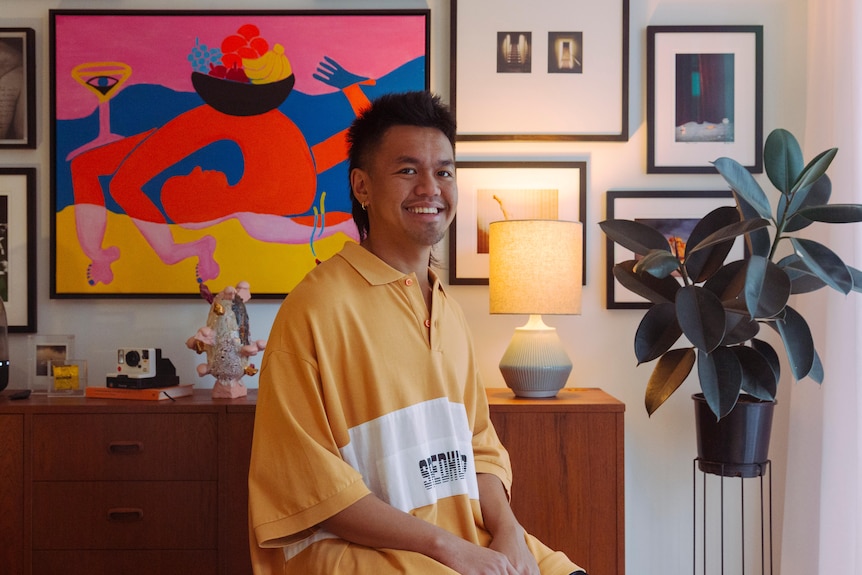 A gender-fluid person with a Filipino  backgrounds poses for a photo in their lounge-room.  