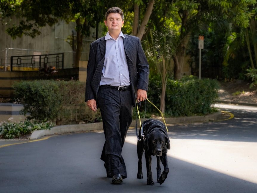 Paul Harpur walking through the UQ campus with his guide dog. 