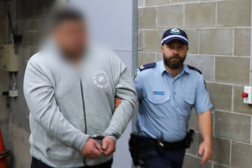 A police man leads a man in handcuffs