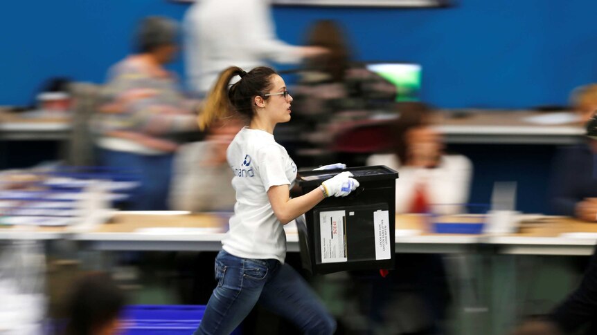 A young woman is pictured running with a ballot box.