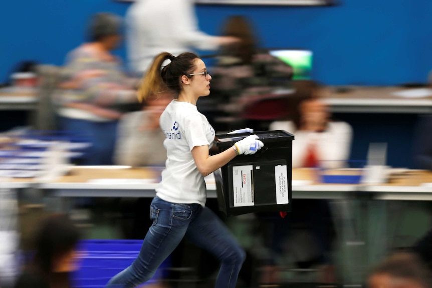 A young woman is pictured running with a ballot box.