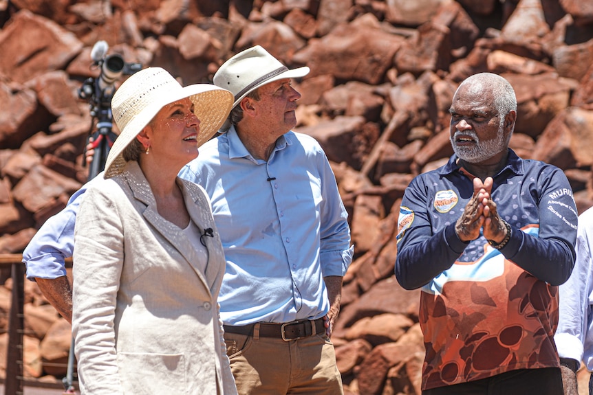 A group of people stand together in front of red rocks.