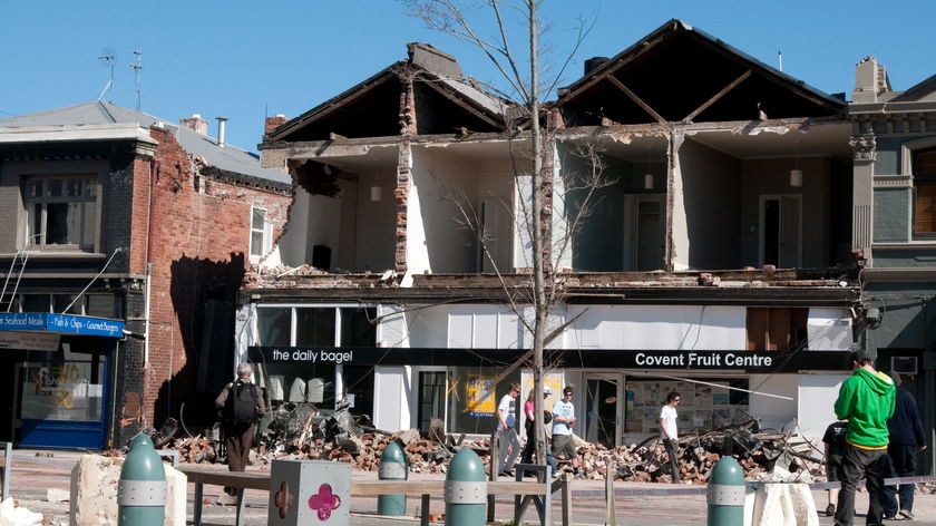 People pass a building which has lost its facade