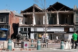 People pass a building which has lost its facade