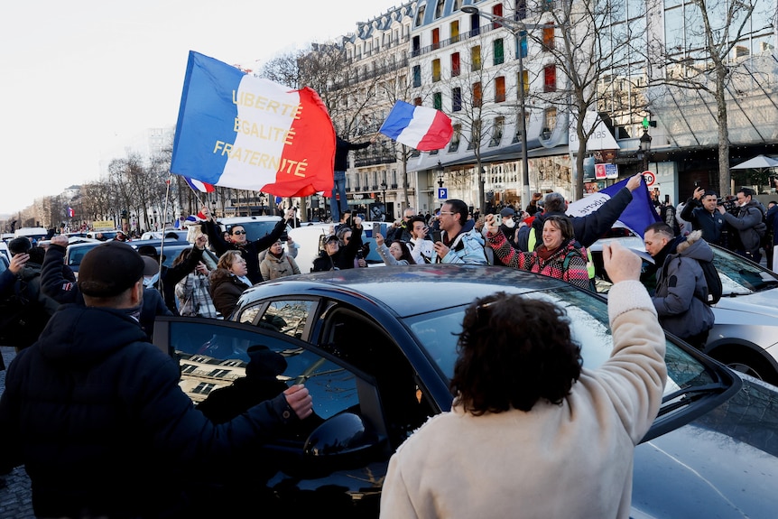 Protesters wave French flags on the Champs-Elysees avenue as cars parade.