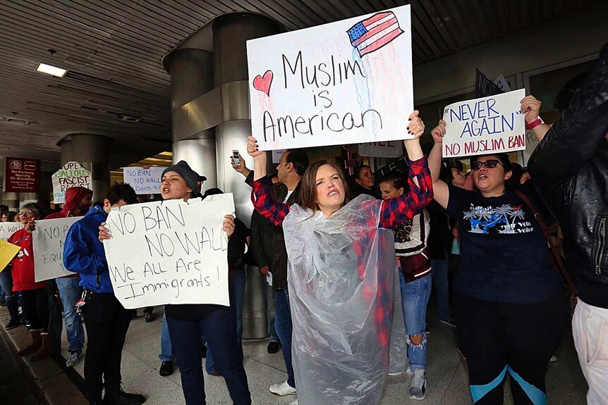 Protesters hold signs reading "Muslim is American" at Miami airport