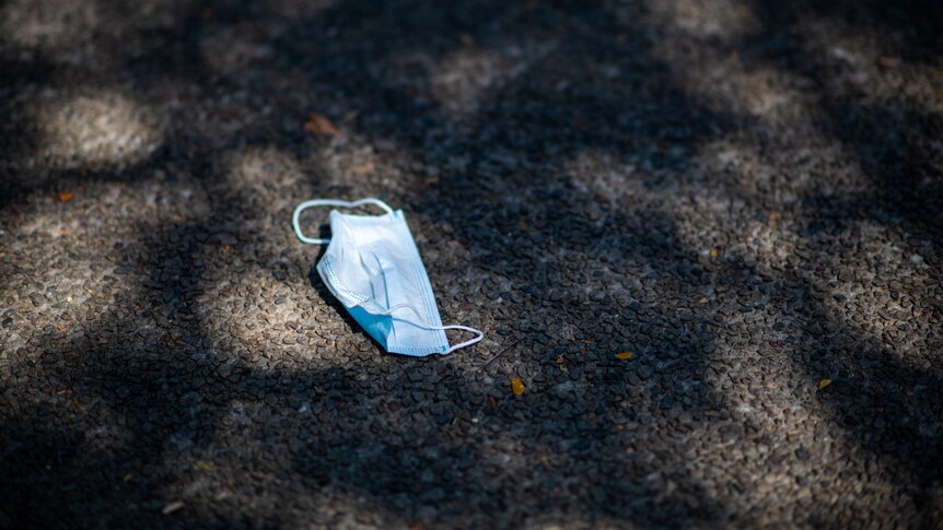A surgical face mask lying on the pavement.