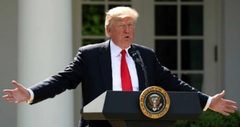 Donald Trump standing at lectern spreading hands wide