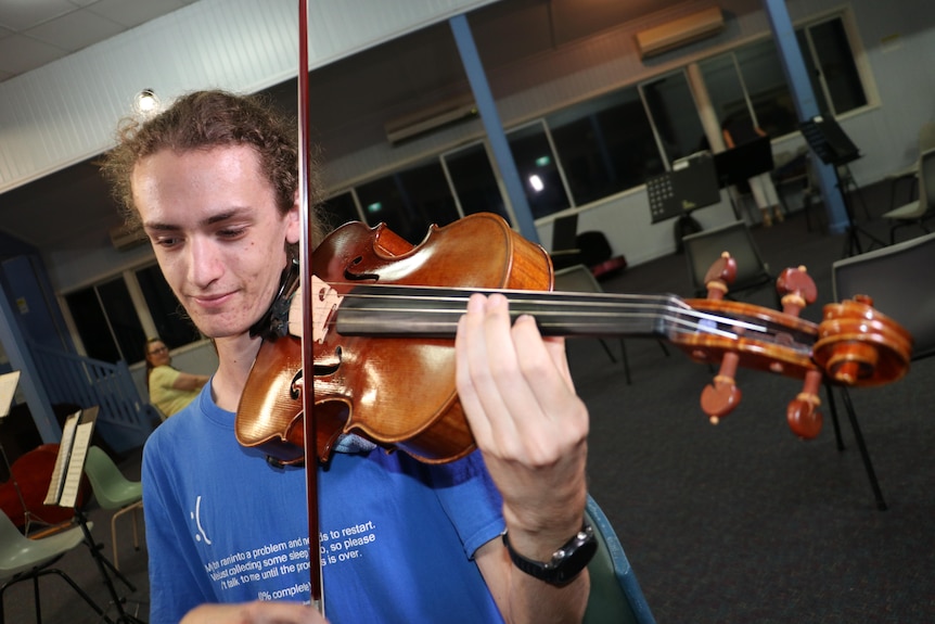 a violinist wearing a blue t shirt plays his instrument