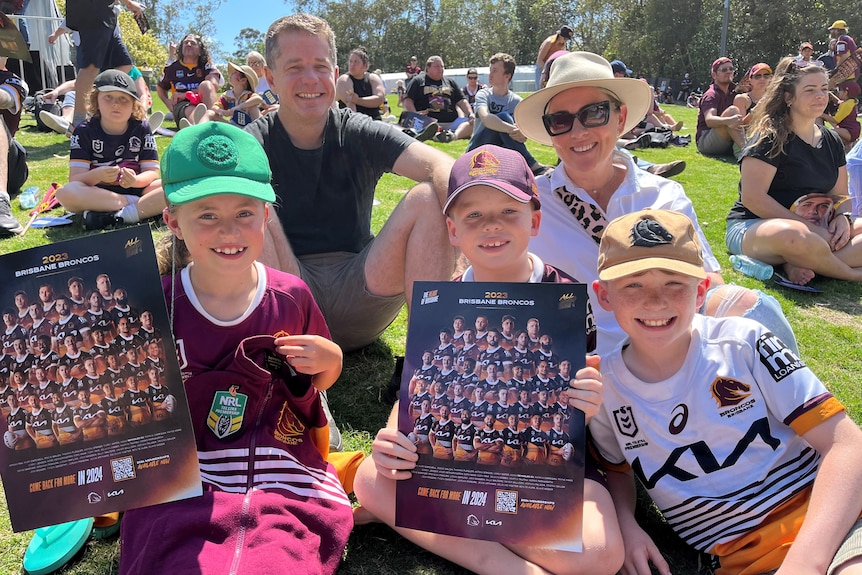 A family wears Broncos merch and holds up signs