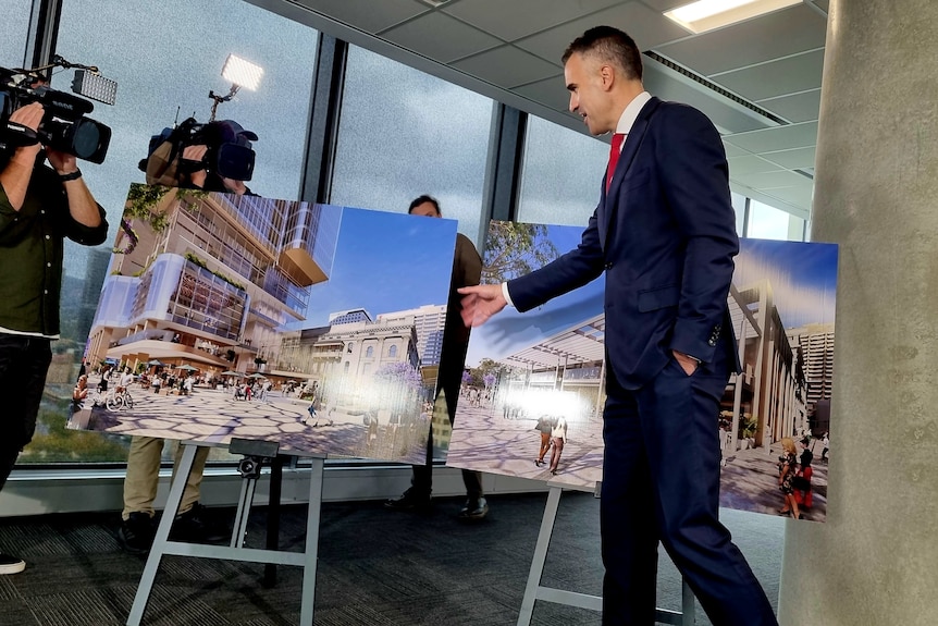 SA Premier Peter Malinauskas is dressed in a suit as he points to pictures of a planned skyscraper.