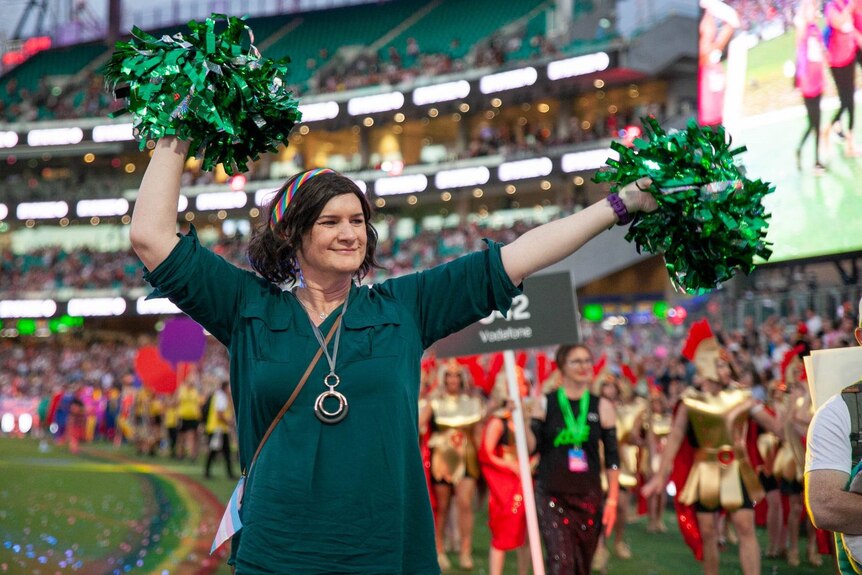 Claire marches in Mardi Gras, waving green pom poms.