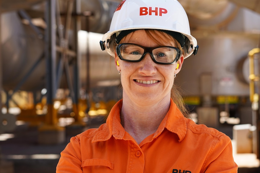 A woman wearing high-vis workwear and a hard hat and safety glasses on a mine site.  