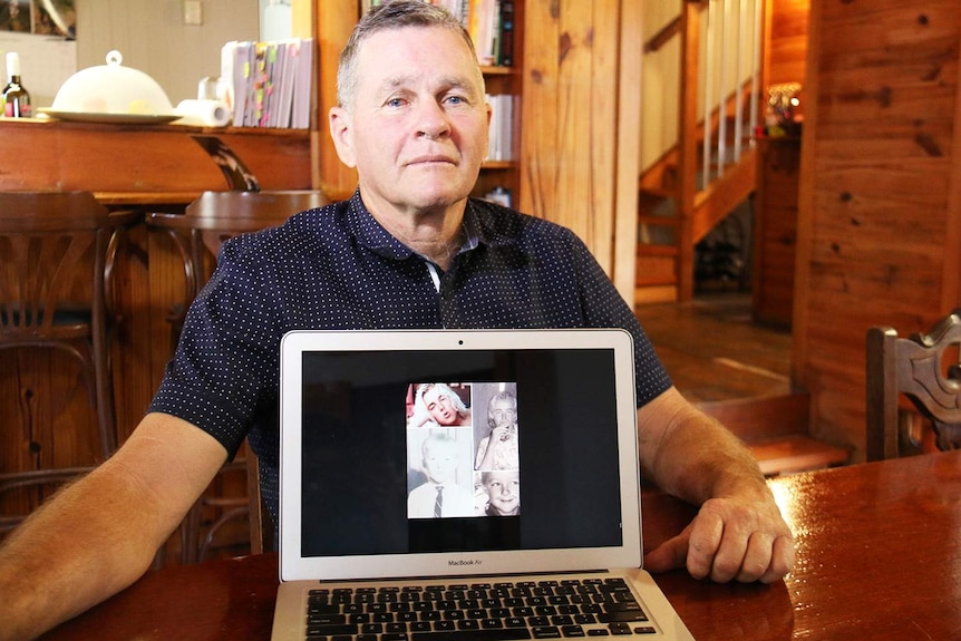 Gary Devitt sits at his dining room table in his home at New Farm in Brisbane, with photos of his missing brother Michael.