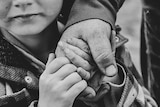 Close up Black and white of small boy's mouth and his hands wrapped around his father's hands