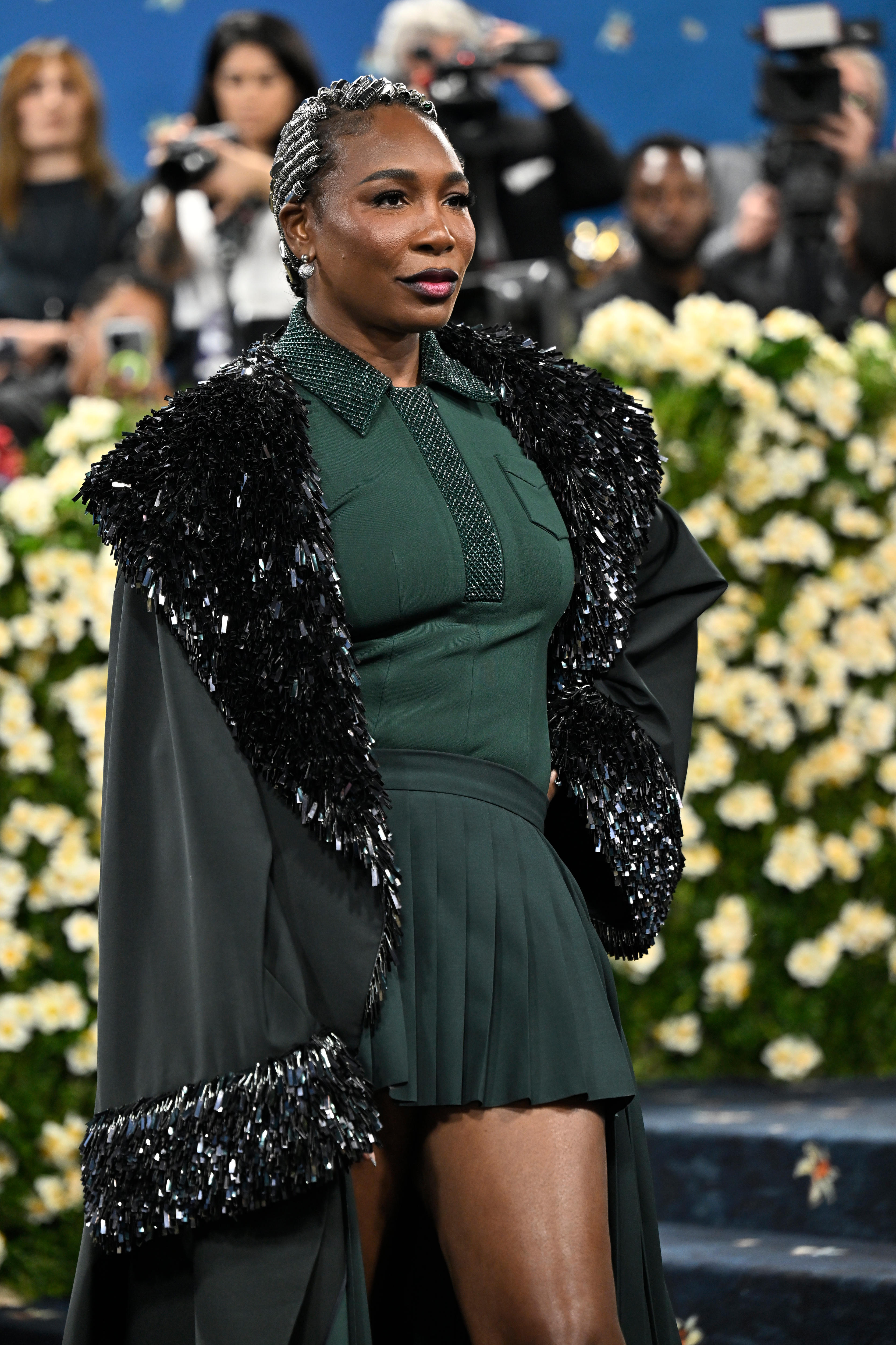 Venus Williams con un vestido verde y un abrigo negro brillante en la Met Gala. 
