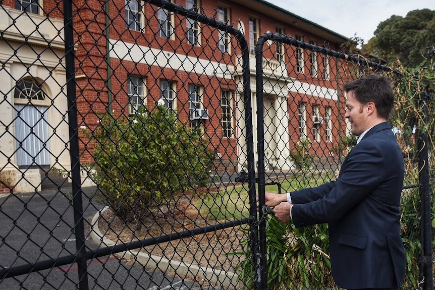 The principal of Preston High School, Sean Butler, locks the gates on the site.