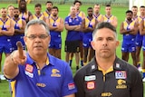 Two men in Eagles shirts, one pointing a stick at the camera, stand in front of players on a football oval.