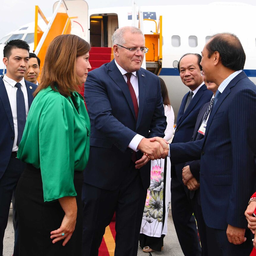 Australian Prime Minister Scott Morrison shakes hands with an official in Vietnam.