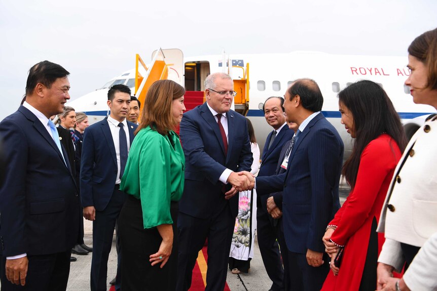 Australian Prime Minister Scott Morrison shakes hands with an official in Vietnam.