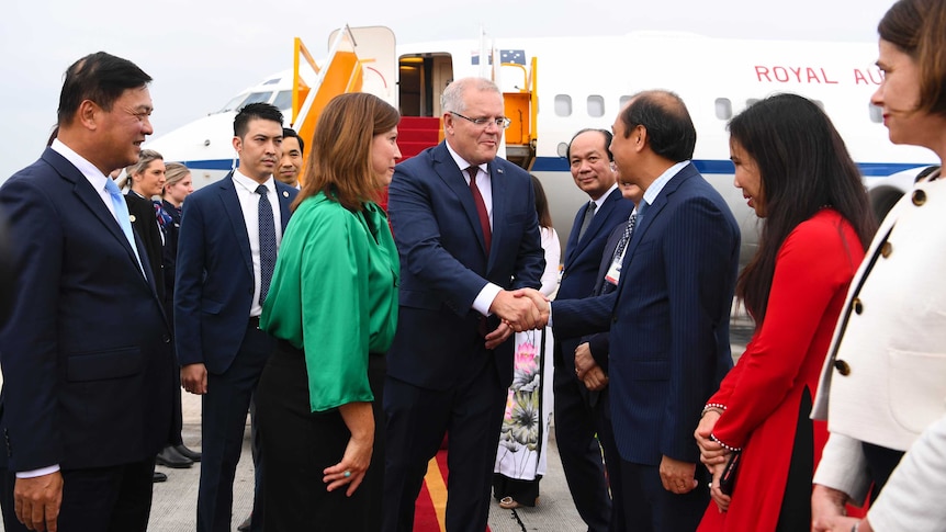 Australian Prime Minister Scott Morrison shakes hands with an official in Vietnam.