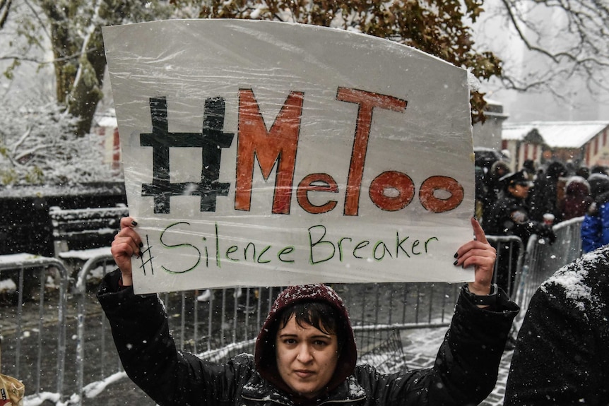 People carry signs at a #MeToo rally