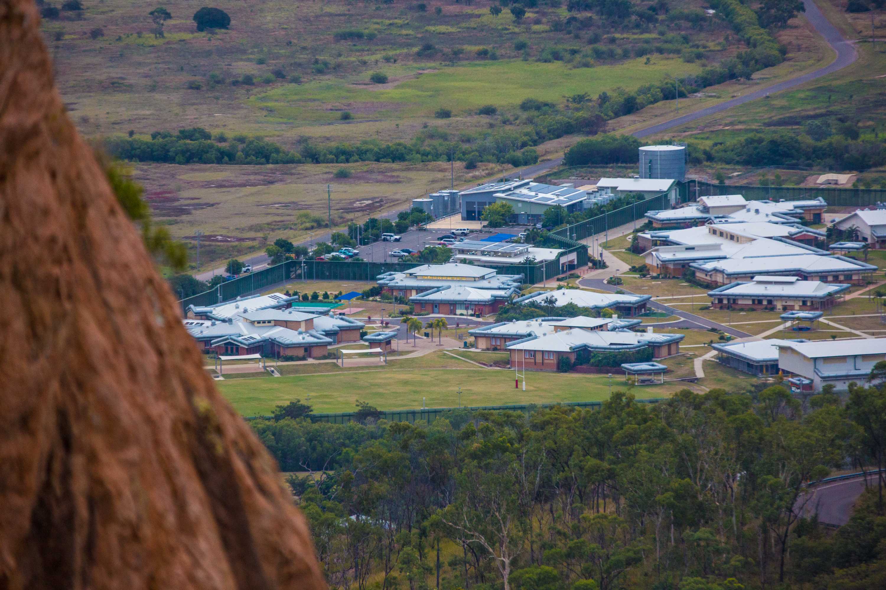 A cluster of buildings in the distance, as pictured from atop a hill