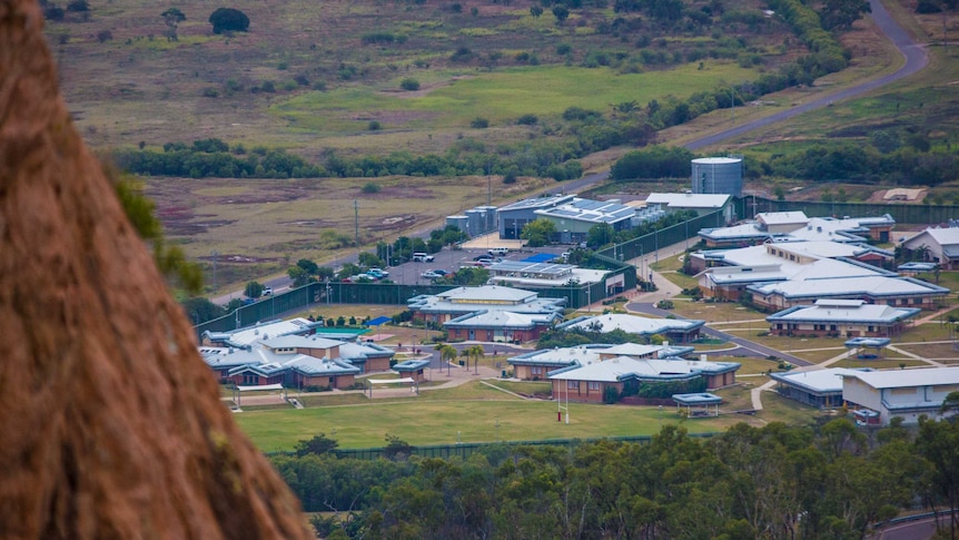 A cluster of buildings in the distance, as pictured from atop a hill