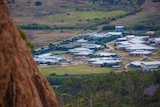 A cluster of buildings in the distance, as pictured from atop a hill