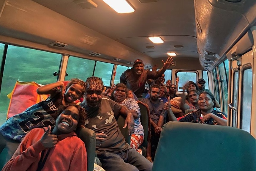 Crowd of people in bus waving and smiling at camera.