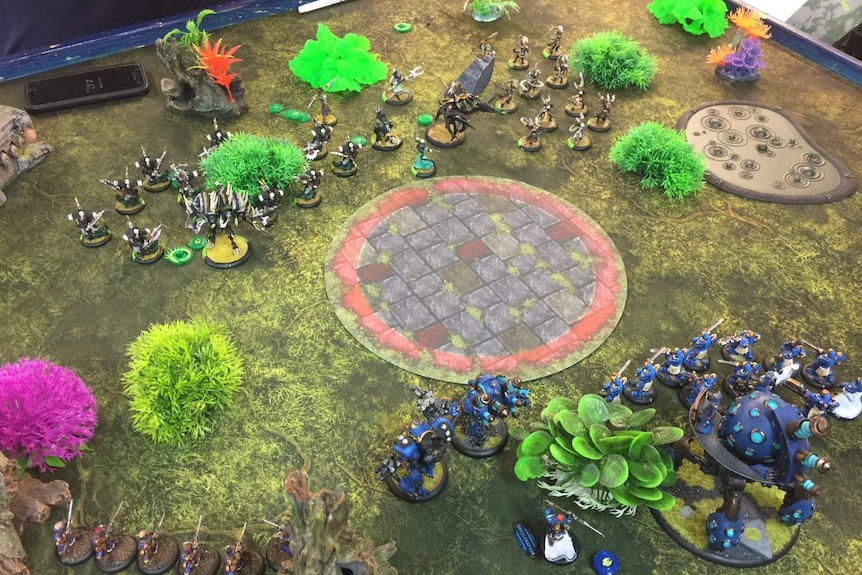 Plastic trees and monster figurines on a board game surface.