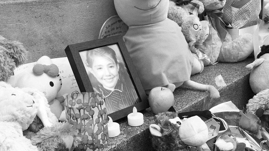 A photo of Thalia Hakin at a memorial where there are also candles and toys.