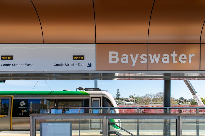 A train arrives at a platform under a Bayswater sign