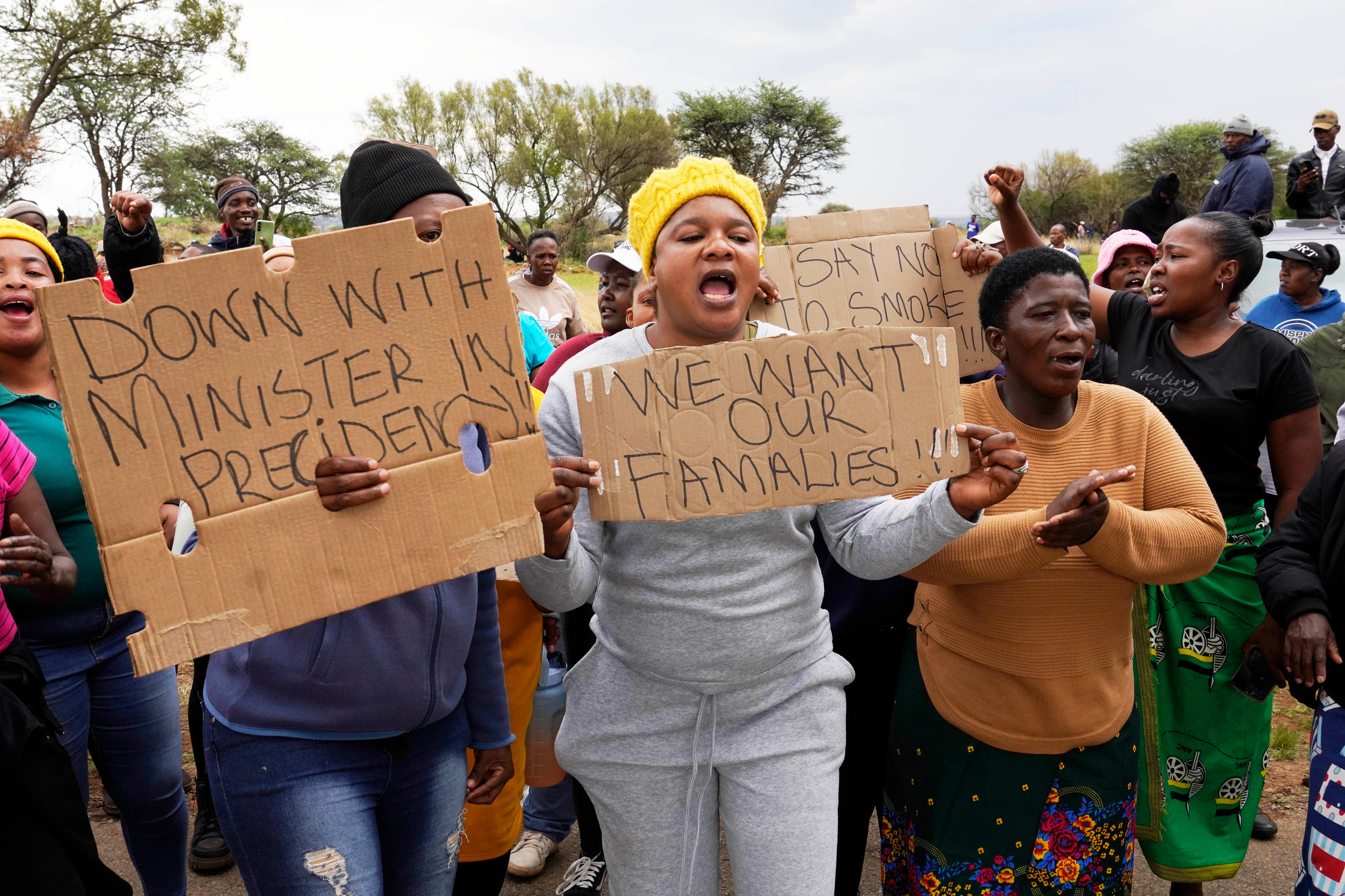 Protesters hold signs saying: "We want our famalies" and "Down with Minister in Precidency".