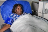 A woman lies in a hospital bed.