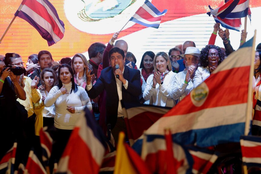 Carlos Alvarado Quesada is seen speaking to a crowd, surrounded by his supporters.