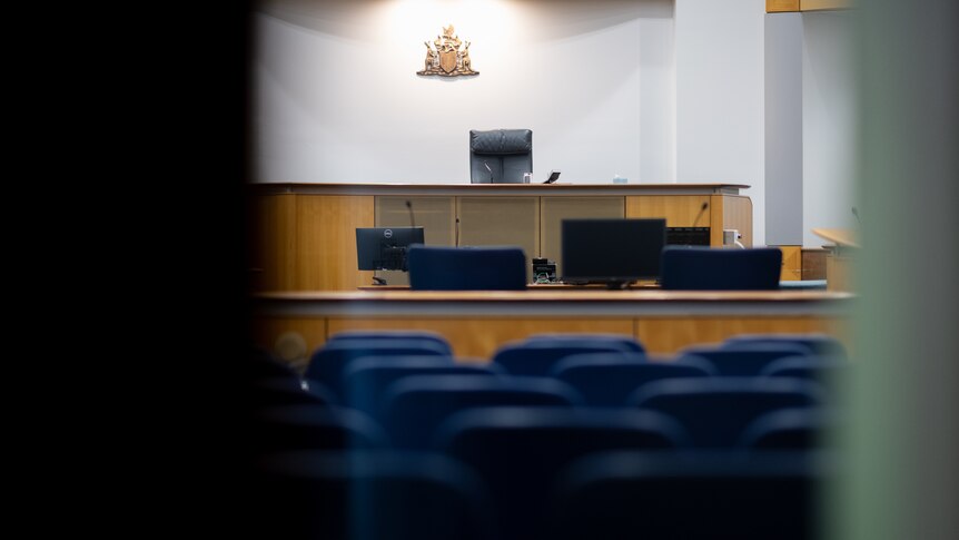 A well-lit courtroom viewed through a doorway. 