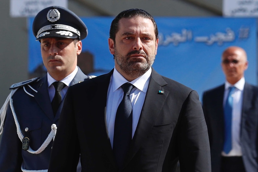 Lebanese Prime Minister Saad Hariri walks next to a military person.