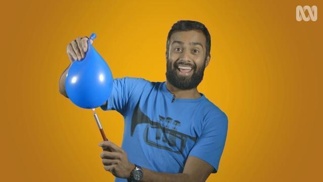 Man holds flame underneath inflated balloon
