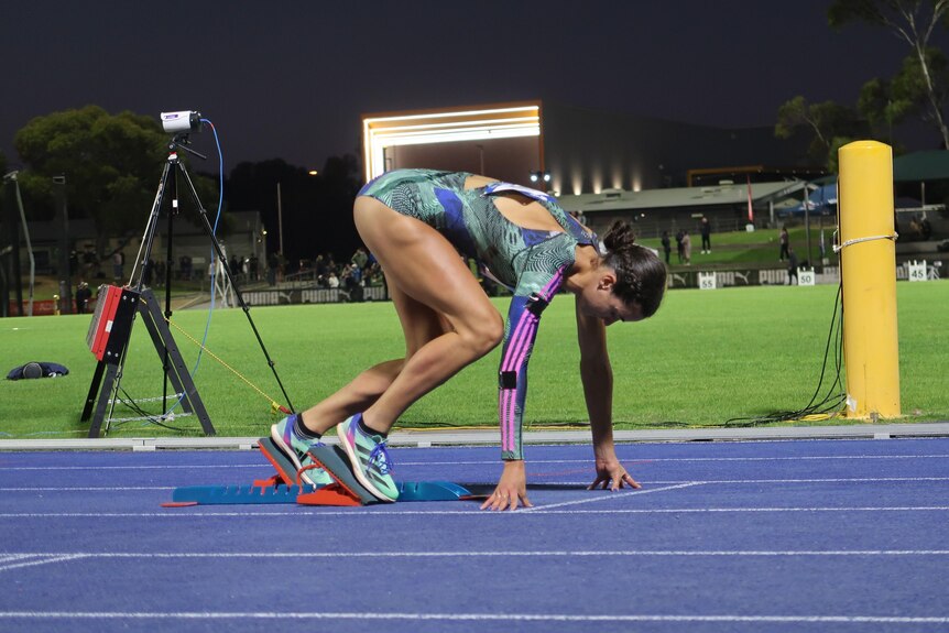 A young female athlete named Alanah Yukic crouches in the starting position.