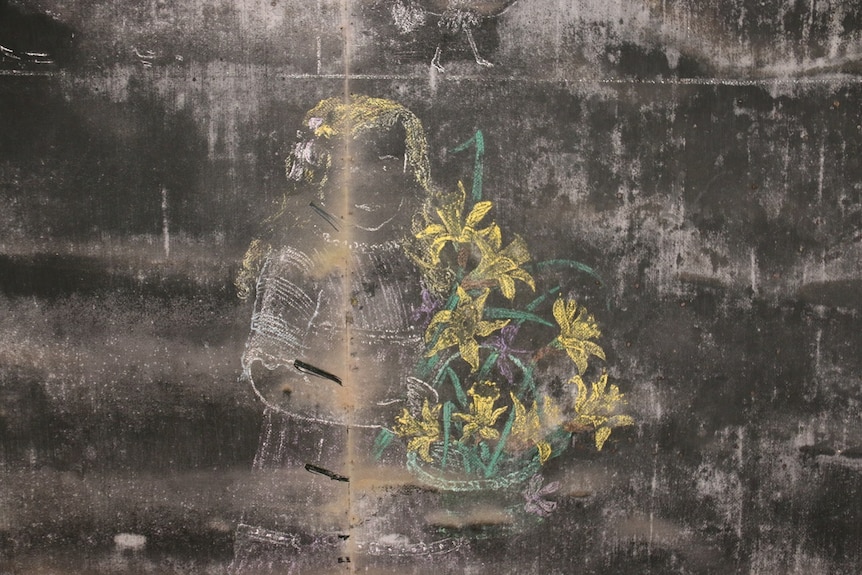 A chalk drawing of a girl with yellow hair holding a basket of flowers on a chalkboard.