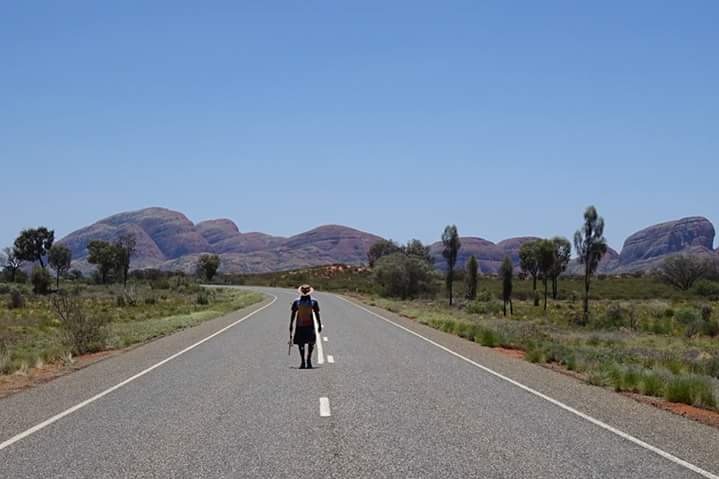 Man walking down the centre of an empty outback road