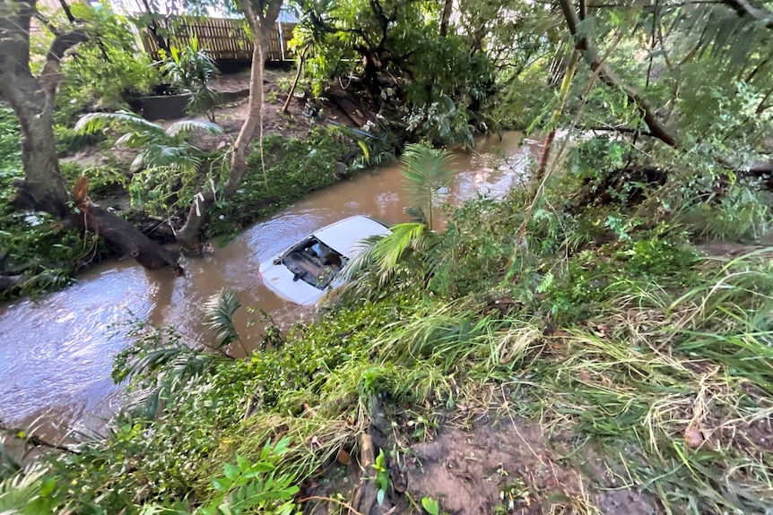 A white sedan submerged in water.