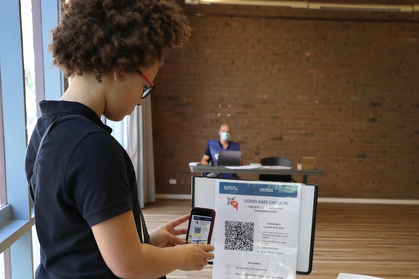 A woman checks in on a QR code using a smartphone